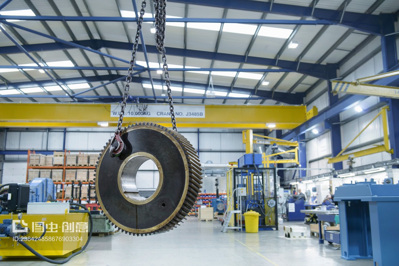 Heavy engineering gear hanging from crane in factory